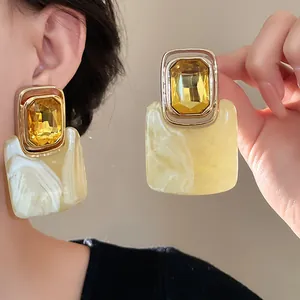 Detailansicht von vintage rechteckigen gelben Steinohrringen mit Marmorharz am Modellohr.