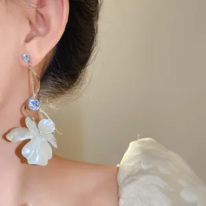Detailansicht eleganter Zirkonia-Blumen-Ohrringe mit weißem Blütenanhänger am Ohr