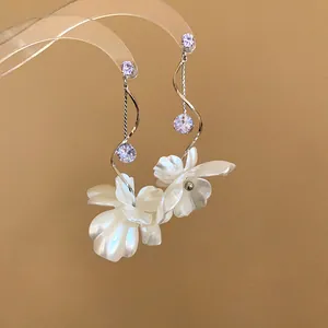 Detailansicht eleganter Blumenequasten-Ohrringe mit Zirkonia auf beigem Hintergrund