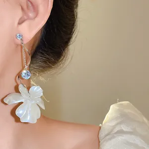 Detailaufnahme der eleganten Silberohrringe mit Zirkonia und weißem Blumendekor.