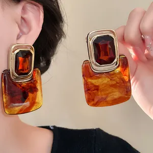 Detailansicht von Vintage-Ohrringen aus Bernsteinharz mit dunklen Edelsteinakzenten.