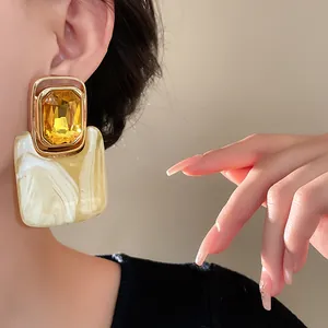 Detailaufnahme von Vintage-Ohrringen mit gelbem Kristall und edler Marmortextur