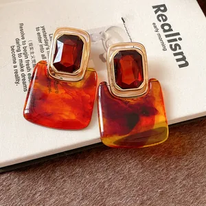 Nahaufnahme von Retro-Ohrringen mit rotem Edelstein und bernsteinfarbenem Harz-Anhänger