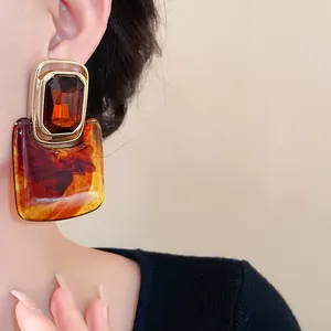 Großaufnahme von großen Bernstein-Resin-Ohrringen am Ohr des Models