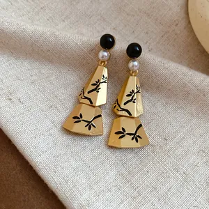 Detail view of new Chinese style gold earrings with pearls and black branch patterns