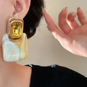 Detailansicht von vintage gelben Edelstein-Ohrringen mit Marmor-Effekt am Modellohr