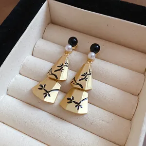 Detail of elegant New Chinese style gold drop earrings with branch patterns and pearls in a box