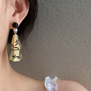 Detailed shot of a vintage Chinese style gold earring with pearl and black branch motifs