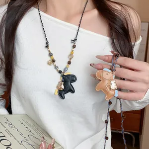 Detailed view of leather horse pendant necklace with colorful wooden beads on model
