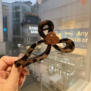 Detail of leopard print hair claw clip with heart motif against city background