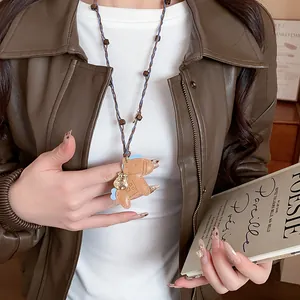 Detail view of a creative leather horse pendant necklace with wooden beads and blue cord