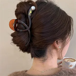 Detailed view of a brown wavy cross hair claw clip with pearl accents on a bun hair style.