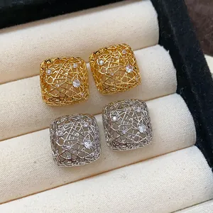 Detailaufnahme von hohlen quadratischen Ohrsteckern in Gold und Silber mit Zirkonsteinen