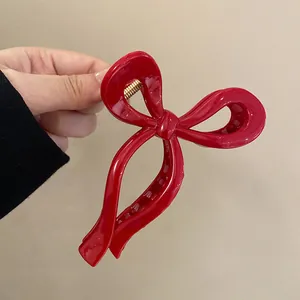 Detailed close-up showing the sleek glossy finish of a red bow-shaped hair claw clip.