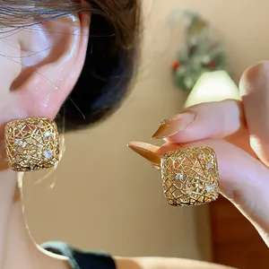 Nahaufnahme von goldenen quadratischen durchbrochenen Ohrringen mit Zirkonia