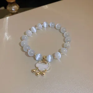 Detail view of ethnic style cat's eye beaded bracelet with a gold Ruyi lock pendant