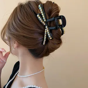 Detailed view of a stylish black rhinestone bow hair claw clip holding a bun elegantly