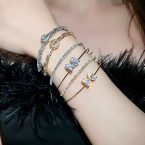 Detailed view of elegant sparkling zircon bow bracelets and double-row bangles on woman's wrist