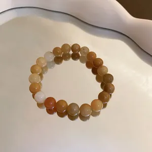 Detailed close-up of a multi-color amber crystal beaded bracelet reflected on a mirror surface.