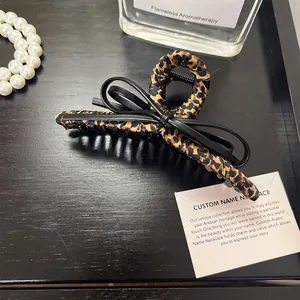 Leopard print hair claw clip with black bow detail on a dark elegant background