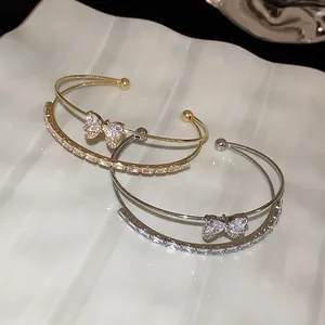 Close-up of elegant double-layered gold and silver bangles with zircon butterfly bow motif