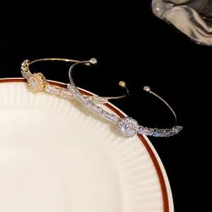 Close-up of silver and gold cuff bracelets with sparkling cubic zirconia on a white plate.