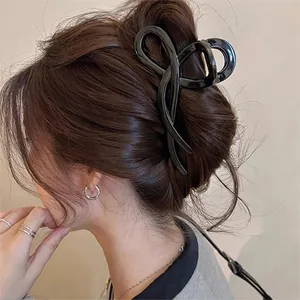 Detail shot of a glossy black wave-shaped hair claw clip securing a stylish bun hairstyle