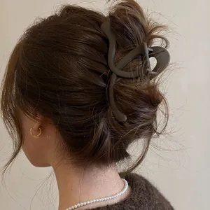 Detailed macro view of a minimalist matte brown cross wave hair claw clip used in a messy bun.