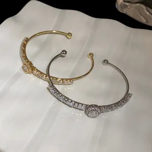 Detailed macro shot of gold and silver plated open cuff bracelets featuring zircon stones