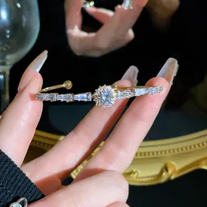 Close-up of elegant gold cuff bracelet with sparkling zircon cluster and baguette stones