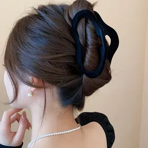 Elegant black wavy hair claw clip shown in a stylish updo hairstyle with pearls
