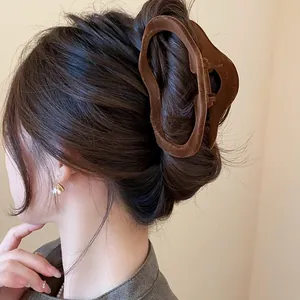 Close-up detail of brown velvet wavy hair claw clip used in a stylish bun hairstyle
