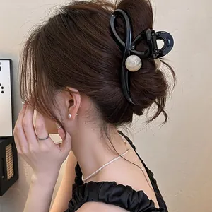Side view of elegant black hair claw clip with pearl details securing a hair bun