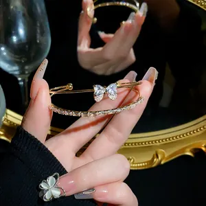 Elegant gold-tone double-row bracelet with zircon bow detail shown against a mirror