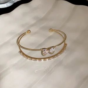 Close-up detail of double-layer gold bangle with butterfly zircon and baguette stones