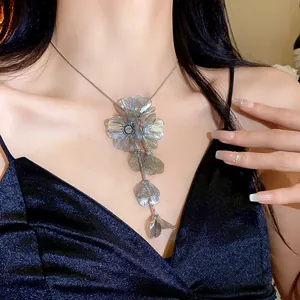 Close-up of oversized silver floral pendant necklace with crystal detail on model