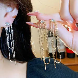 Primo piano di eleganti orecchini a nappa lunga con perni in zircone e delicate catenelle.