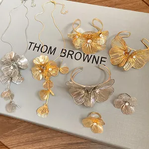 Detailed view of gold and silver floral jewelry set with rhinestone accents on grey board