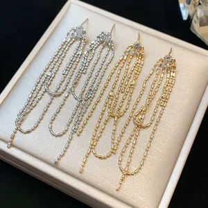 Primo piano di eleganti orecchini a nappa lunga in oro e argento con zirconi tondi