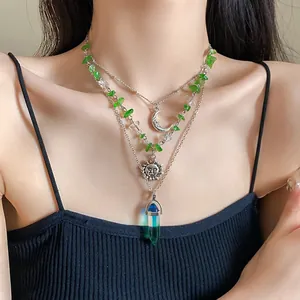 Close-up of retro layered necklaces with sun, moon, and green crystal on model