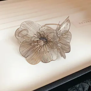 Close-up of elegant silver hollow flower cuff bracelet with sparkling center rhinestone.