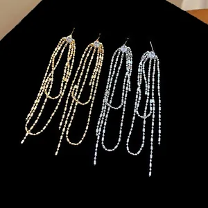 Dettaglio di orecchini a nappa in oro e argento con zirconi rotondi lucidi.