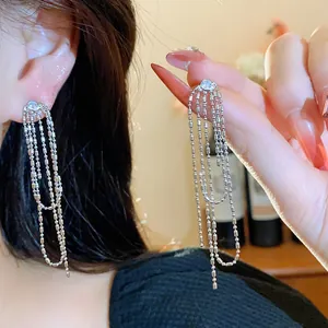 Dettaglio di orecchini minimalisti in argento con zircone rotondo e nappine a catenella