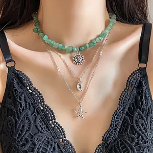 Detailed view of layered necklace featuring green stones with sun, moon, and star pendants.