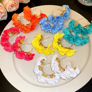 Detailed view of multiple colorful chiffon flower C-shaped earrings displayed on a plate