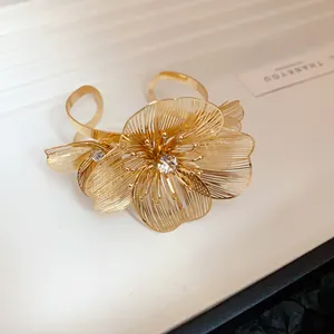 Detailed view of the delicate gold hollowed flower design with sparkling center crystal