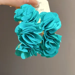 Close-up of teal chiffon flower C-shaped earrings with soft layered petals