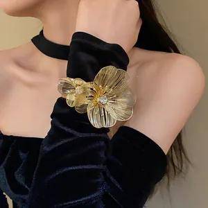Close-up of a gold filigree flower cuff bracelet with rhinestone detail on velvet