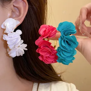 Close-up of large chiffon flower C-shaped earrings in white, red, and teal colors.