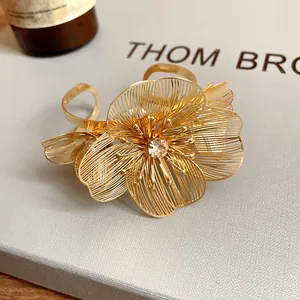Detailed view of gold filigree flower cuff bracelet with center crystal stone.